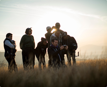 Group of people looking at a phone together in a field